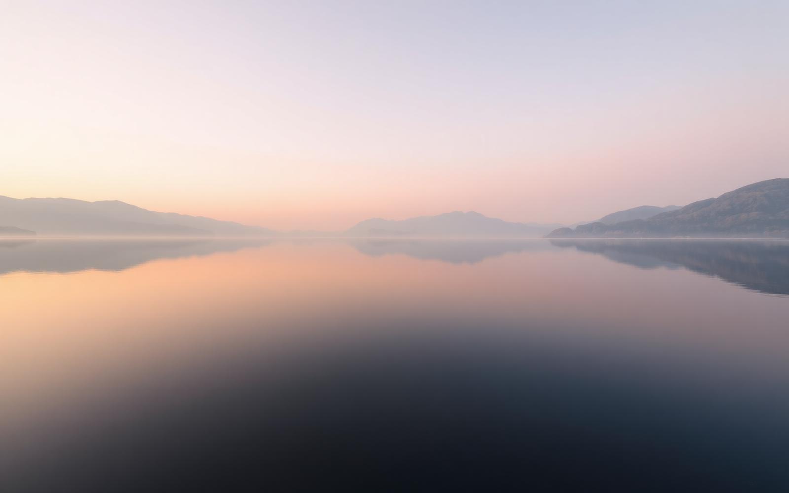 Still lake at dawn reflecting pastel sky